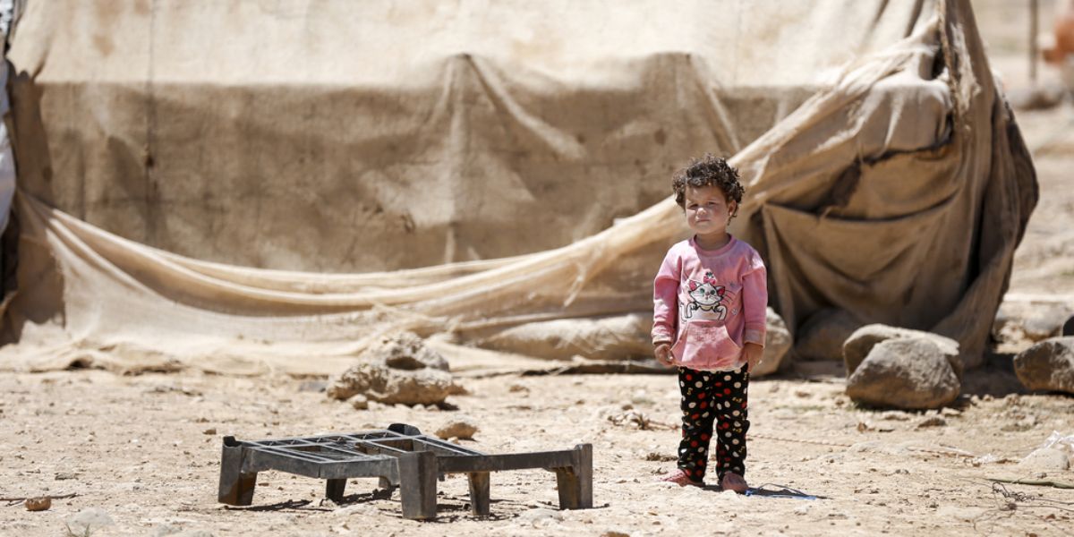 A syrian refugee child in front of his tent